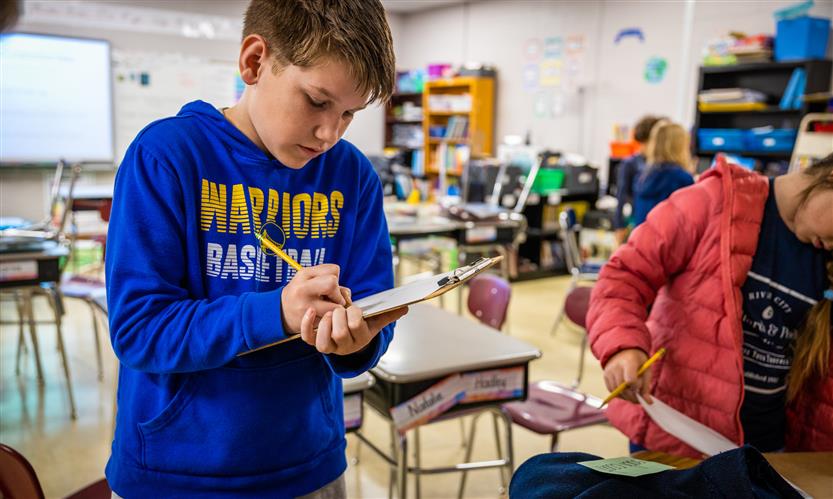 A boy wearing a blue shirt looks at an item from the traveling trunk